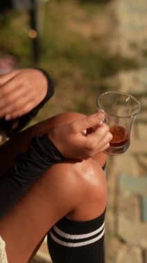 Huzurlu ve sakin bir sahne. Güneşli bir zemine karşı bir bardak çayı nazikçe tutan bir el.