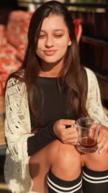 Güzel ve huzurlu bir an, bir kadının çayının tadını şık ve rahat bir atmosferde çıkarmasını sağlıyor.