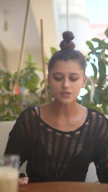 Genç bir kadın enerjiyle dolu canlı ve canlı bir kafe atmosferinde kendini tutkuyla ifade ediyor.