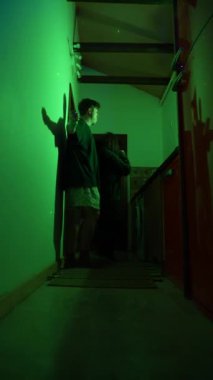 Yalnız bir insan loş bir koridorda duruyor, bitişik duvarda ilgi çekici ve karmaşık gölgeler bırakıyor.