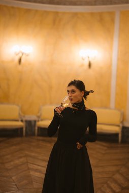 Şık, şık ve davetkar bir ortamda zarif bir şekilde şampanya bardağı tutan sofistike bir kadın.