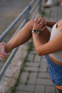 Atletik bir insan bacağını esnetiyor, canlandırıcı bir koşuya hazırlanıyor, sağlık ve uygunluğu somutlaştırıyor.