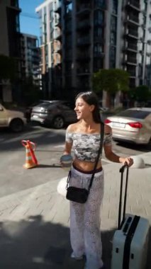 Moda ve modaya uygun bir gezgin canlı ve hareketli bir şehir caddesinden zevk alıyor, bavul elinde ve atıştırmalıklar hazır.