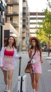 İki şık genç kadın ellerinde şık bavullarla şehir merkezinde dolanıp yaz yolculuğunun özünü yakalıyorlar.