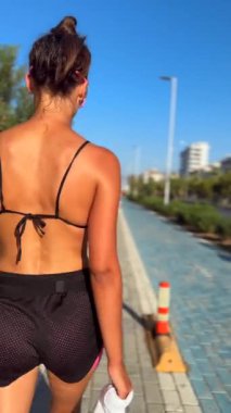 Genç bir kadın şık bir atletizm elbisesi içinde yürürken güneşli bir günün tadını çıkarır..