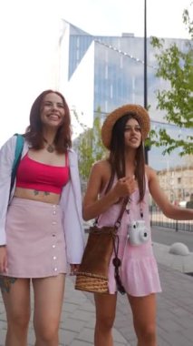 İki modaya uygun kadın, gençlik enerjisi ve moda tarzıyla canlı şehir sokaklarında geziniyor.