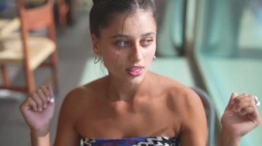 Genç bir kadın zarif ve renkli bir elbise içinde poz veriyor, duruşunu ve derin düşüncelerini güzelce sergiliyor.