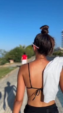 Kaygısız bir yaz gününde neşe ve rahatlıkla dolu genç bir kadın güzel manzaralı bir patikada geziniyor.