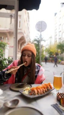Rahat bir kafede sushi yiyen bir kadın rahat bir şehir yemeği deneyimi sergiliyor.