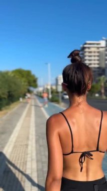 Şık bir kadın, güneşli bir gezinti güvertesinde, yaz modasını ve ışıl ışıl cildini sergiliyor.