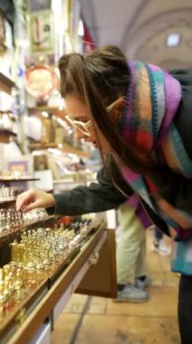 Bir kadın canlı ve hareketli bir pazar atmosferinde karmaşık ve güzel mücevher parçalarını inceliyor.