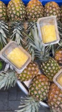 Renkli ananaslar hareketli bir pazarda güzel bir şekilde sergilenir, her yerde yemek severler için mükemmeldir.