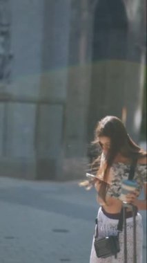 Şık, genç bir kadın telefonuna dalmış enerjik bir şehir ortamında gezinirken.