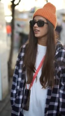 Şık bir insan günlük şehir kıyafetleri giyer, modaya uygun bir bere giyer ve açık havada şık bir güneş gözlüğü takar.