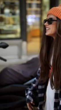 Modayı takip eden genç bir kadın büyük bir fanila gömlek ve çarpıcı turuncu bir bere giyer.