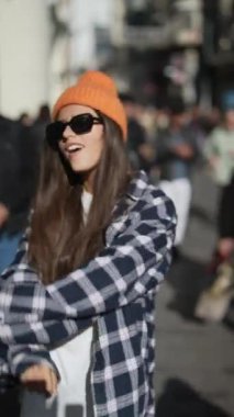 Şık, genç bir kadın, en son moda eğilimlerini zahmetsizce sergileyerek kentteki kıyafetine güvenerek poz veriyor.