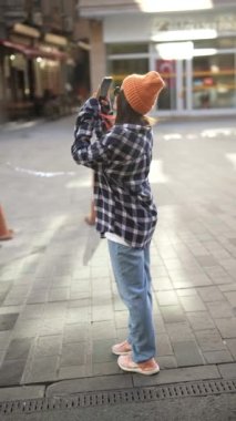 Havalı ve modaya uygun bir birey rahat giyinmiş, hareketli şehir manzarasının fotoğraflarını çekiyor.