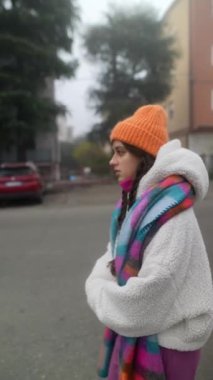 Serin ve sisli bir günde şık bir kış elbisesi içinde genç bir kadın dışarıda duruyor, atmosferi kucaklıyor.