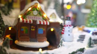 Sıcak zencefilli kurabiye evi ve karlı dekorun ortasında neşeli bir kardan adamın yer aldığı şenlikli bir minyatür sahne.