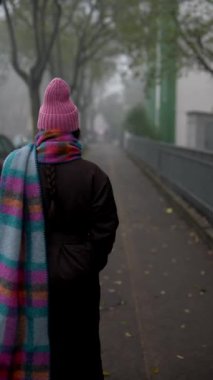 Renkli bir eşarba sarılmış, sisli bir caddede yavaşça yürüyen bir insanın huzur dolu ve huzurlu bir sahnesi.