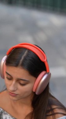 Moda kulaklıklı genç bir kadın açık havada eğlenirken büyüleyici müziğe daldı.