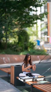 Meditasyon yapan genç bir kadın, canlı ve bereketli bir kentsel çevre ile çevrili bir bankta oturuyor.