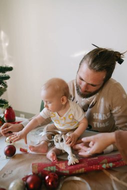 Sevgi dolu bir ebeveynin ve bebeğinin birlikte Noel hazırlıklarının keyfini çıkardığı iç açıcı bir sahne.