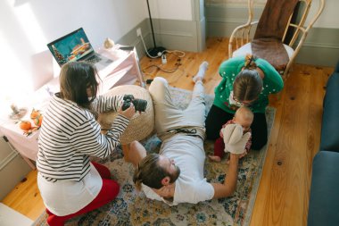 Neşeli bir aile etkileşimi. Güneşli bir oturma odasında gülücüklerin ve neşeli anların özünü yakalıyor.