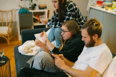 Yakın arkadaşlar rahat bir kanepede rahatlar, içkilerini paylaşır ve kahkahalarla dolu neşeli anların tadını çıkarırlar.