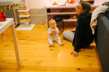 Yürek ısıtan bir sahne, sevgi dolu bir annenin sevimli bebeğiyle şık bir evde şefkatle etkileşim kurduğunu gösteriyor.