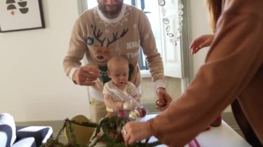 Neşeli bir aile mutlu bir şekilde yaklaşan bayrama hazırlanıyor. Şirin bir bebek ve canlı bir şenlik süslemeleri var.