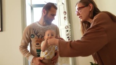 Sevgi dolu bir çift ve sevimli bebekleriyle kapalı bir ortamda neşeli ve iç açıcı bir aile anı.