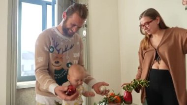 Noel kutlaması sırasında her yerde bir bebek ve şenlik süslemeleri olan neşeli bir aile anı.