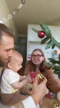 Güzel dekore edilmiş bir Noel ağacının etrafında neşeli bir ailenin toplandığı hoş bir tatil sahnesi.