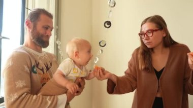 Sevgi dolu bir ebeveynin ve sevimli bebeklerinin kapalı alanlarda oyun oynadığı neşeli bir aile anı.