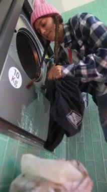 Canlı ve renkli bir çamaşırhane atmosferinde çamaşırhane işleriyle uğraşan modaya uygun ve şık bir birey.