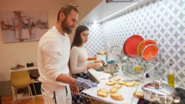 Mutlu bir çift, modern bir mutfakta birlikte yemek pişirir. Takım çalışması ve yemek pişirme becerileri sergilerler.