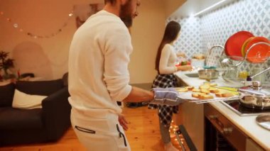 Neşeli bir çift, sıcak ve hoş bir mutfak ortamında lezzetli ve lezzetli yemekler hazırlıyor.