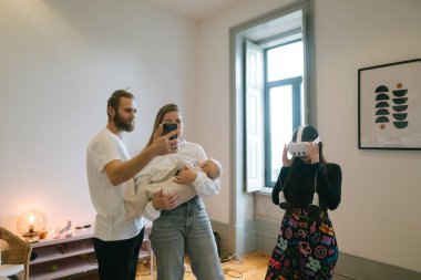 Sevgi dolu bir aile, evlerinde rahat bir ortamda akıllı telefonları kullanarak bebekleriyle değerli anılarını yakalar.