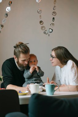 Sevgi dolu bir çift, sevimli bebekleriyle sıcak bir kafe ortamında keyifle güzel bir anı paylaşır.