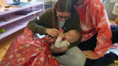 Sevgi dolu bir ailenin neşeli bir kutlamada neşeli bir bebekle bayram hediyelerini açması gibi neşeli bir an yaşanıyor.
