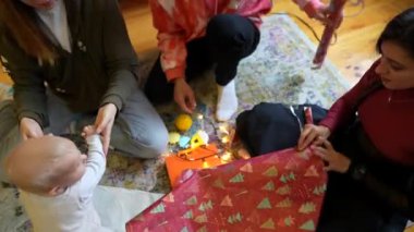 Hediye paketlemenin ve birlikteliğin sıcaklığını vurgulayan yürek ısıtan bir aile sahnesi.