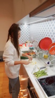 İki insanın yemek pişirme ve birlikte yemek hazırlama sanatının keyfini çıkardığı sıcak ve samimi bir mutfak sahnesi.