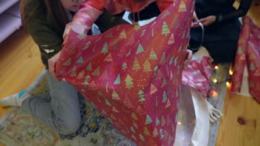 Neşeli tatil kağıtları ve renkli süslemelerle süslenmiş neşeli hediyeleri paketlemenin hazzını yakalıyorum.