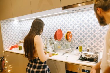 Bir çift modern mutfaklarında birlikte yemek yapmayı, takım çalışmasını ve sıcaklığını sergilemeyi seviyor.