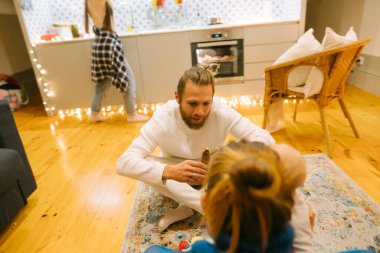 Sıcak ışıklandırmayla süslenmiş rahat, şık bir yaşam alanında aile içi etkileşimin keyifli ve keyifli bir anı yaşanıyor.