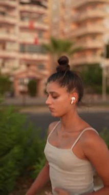 Genç bir kadın şehir merkezinde enerjik bir şekilde koşuyor. Gün batımında zindelik ve zindeliği kucaklıyor.