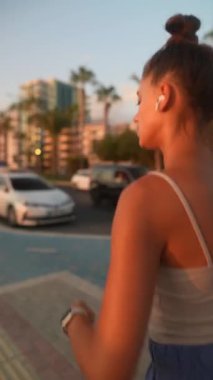 Genç bir kadın hayat dolu bir şehir ortamında nefes kesici bir günbatımında enerjik ve tutkulu bir şekilde koşar.