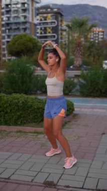 Formda ve enerjik bir kadın gün batımında güzel ve manzaralı bir şehir ortamında etkin bir şekilde egzersiz yapar.