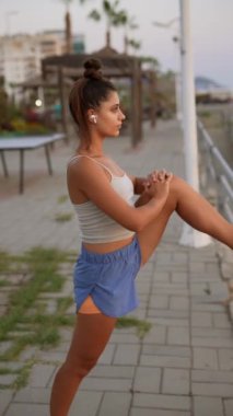 Bir kadın zarif bir şekilde bacaklarını dışarı uzatır, müziğe dalmış, huzur içinde günbatımından zevk alır.